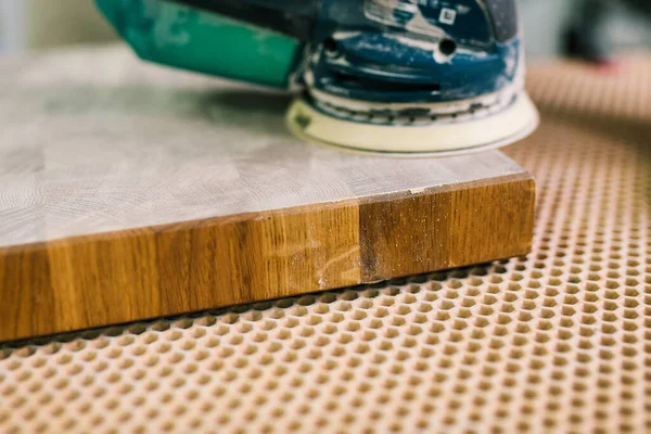 Timmerman poetst een houten plaat in een werkplaats. Het proces van de slijpmachine. Productie van houten meubels. Delen van slijpen — Stockfoto
