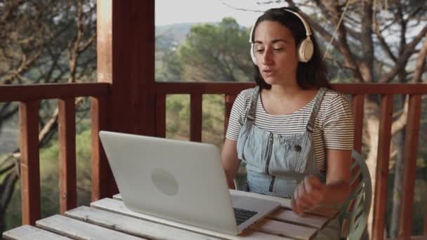 Mujer hispana usando computadora portátil para videollamadas en la terraza del hogar — Vídeos de Stock