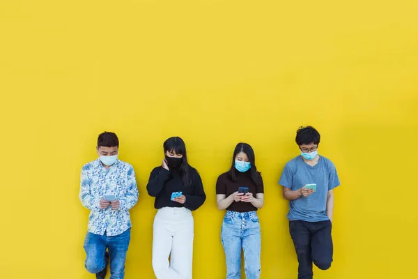 Amigos asiáticos em máscara protetora usando smartphone ao ar livre — Fotografia de Stock