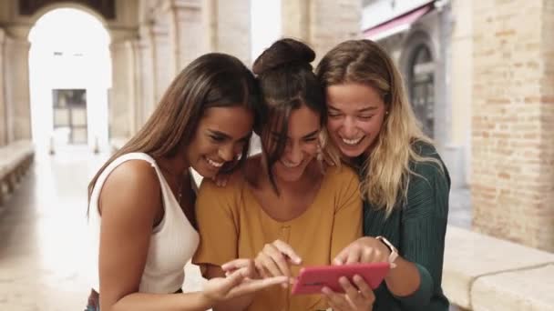 Multikulturelle Freundinnen lachen, während sie Social-Media-Inhalte am Telefon ansehen — Stockvideo