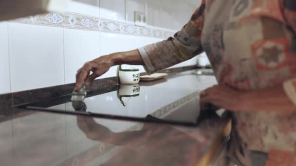 Старшая женщина ручная уборка кухни электрическая керамическая плита с скребком — стоковое видео