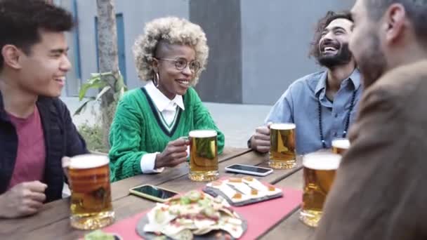 Grupo de amigos multirraciales animando con cervezas en terraza bar — Vídeos de Stock