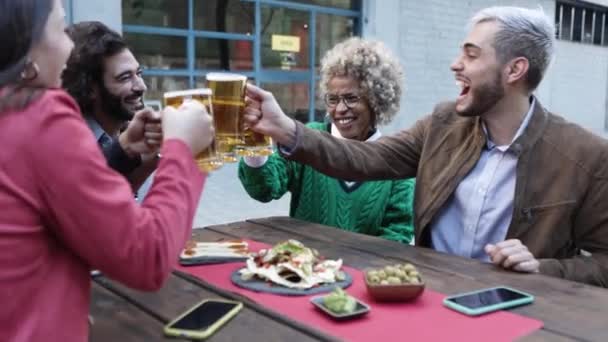 Fröhliche junge Leute feiern nach Feierabend gemeinsam beim Biertrinken — Stockvideo