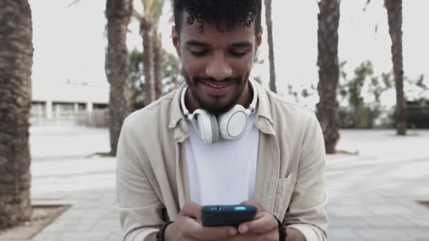 屋外で携帯電話を使用して若い男のフロントビュー — ストック動画