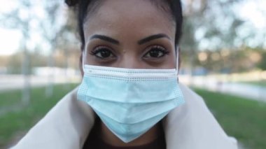 Koruyucu yüz maskesi takan Afrikalı Amerikalı genç kadının yakın portresi.