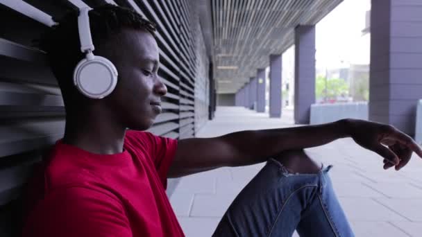Χαρούμενος Αφροαμερικάνος με ακουστικά που ακούει μουσική στο κινητό — Αρχείο Βίντεο