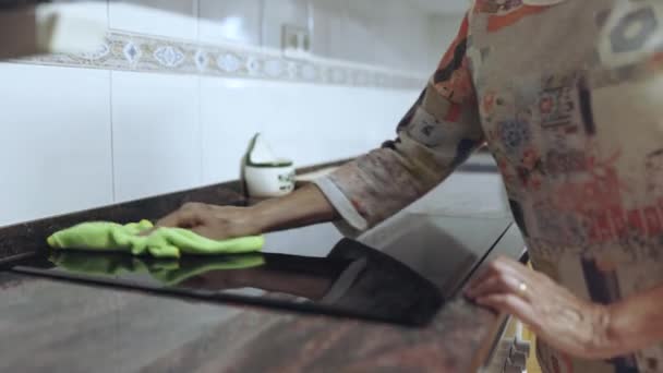 Starsza kobieta sprzątanie ręcznie kuchnia elektryczna płyta ceramiczna z mikrofibry tkaniny — Wideo stockowe