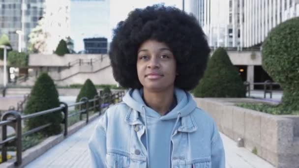 Młoda, latynoska kobieta z afro fryzurą spacerująca ulicą miasta — Wideo stockowe