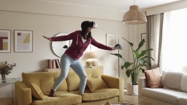 Woman having fun while surfing on sofa using virtual reality glasses at home — Stockvideo
