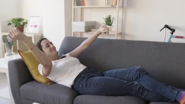 Cheerful young adult woman listening her favourite song on wireless headphones — Stock videók