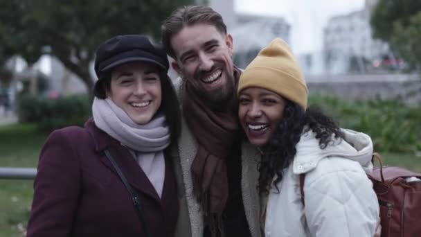 Three happy multiracial friends in winter clothes standing together in city — Vídeo de Stock