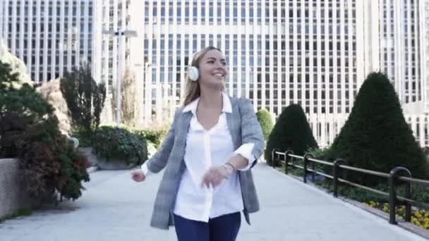 Счастливая молодая деловая женщина слушает музыку и танцует в финансовом районе — стоковое видео