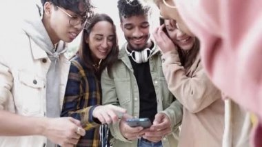 Genç arkadaşlar birlikte gülüyor cep telefonundan sosyal medya içeriğini izliyorlar 