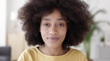 Afrikalı Amerikalı bir kadın kameraya video aracılığıyla bakıyor ve dinliyor.