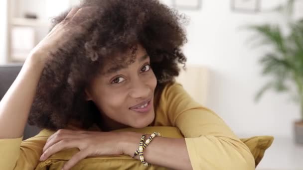 Primo piano giovane donna africana americana sorridente alla macchina fotografica mentre si rilassa a casa — Video Stock