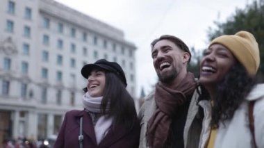 İki kadın ve bir erkek birlikte gülüyor ve dışarıda eğleniyorlar.