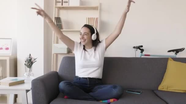 Mujer joven escuchando música con auriculares inalámbricos y bailando en casa — Vídeo de stock