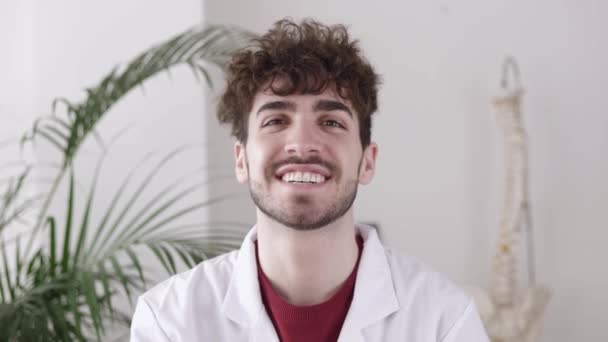 Portrait de jeune médecin dans son cabinet médical souriant à la caméra — Video