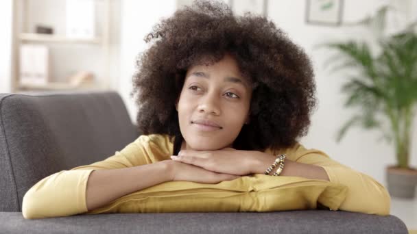 Jovem mulher afro-americana atenciosa olhando para longe enquanto relaxa no sofá. — Vídeo de Stock