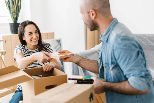 Ευτυχισμένο νεαρό ζευγάρι ξεπακετάρισμα χαρτονένια κουτιά, ενώ κινείται σε νέο διαμέρισμα — Φωτογραφία Αρχείου