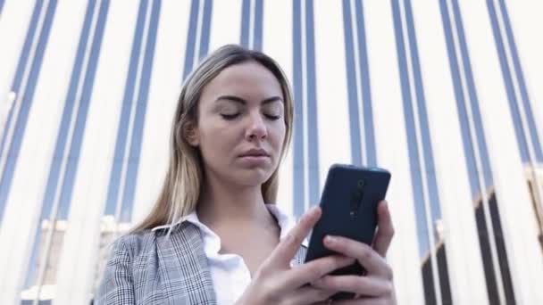 Jovem empresária confiante usando telefone celular no distrito financeiro — Vídeo de Stock
