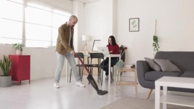 Bıyıklı adam evde süpürgeyle yerleri temizliyor.