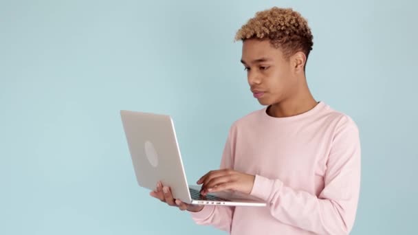 Jovem adolescente preocupado lendo más notícias no laptop contra fundo azul — Vídeo de Stock