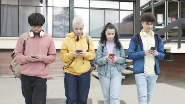 Skupina multiraciálních teenagerů používajících mobilní telefony po škole — Stock video