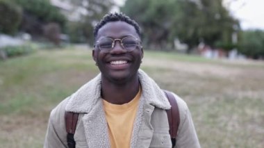 Dışarıda kameraya bakan gülümseyen Afrikalı genç bir öğrenci.