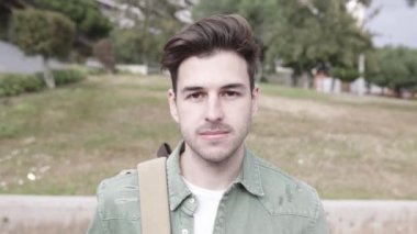 Kampüsteki üniversitede kameraya gülümseyen son moda yakışıklı genç öğrenci.