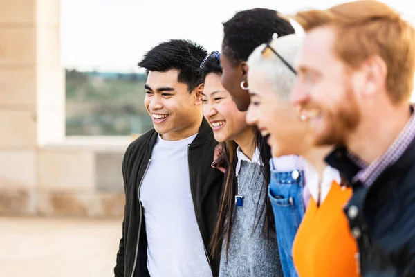 Різноманітна група об'єднаних молодих друзів сміються разом на відкритому повітрі — стокове фото