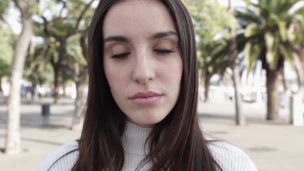 Portret van jonge serieuze vrouw op zoek naar camera buiten — Stockvideo