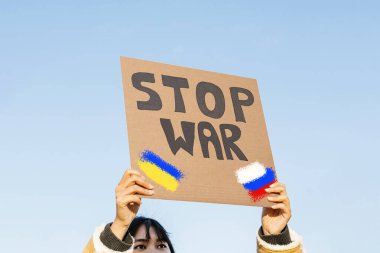 Genç Asyalı kadın, Rus ordusunun Ukrayna 'yı işgalini protesto ediyor.