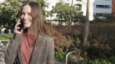 Doğu Avrupalı genç kadın şehir caddesinde cep telefonuyla konuşuyor 