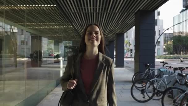 Femme souriante à la mode portant un costume décontracté marchant dans le bureau après le travail — Video