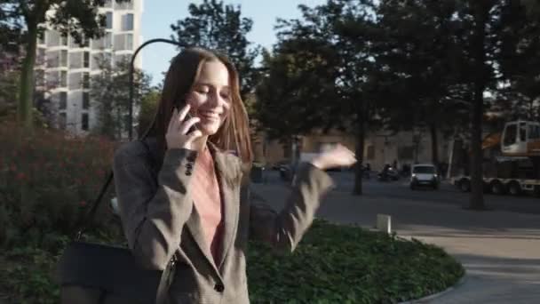Gülümseyen genç iş kadını şehir caddesinde telefonla konuşuyor. — Stok video