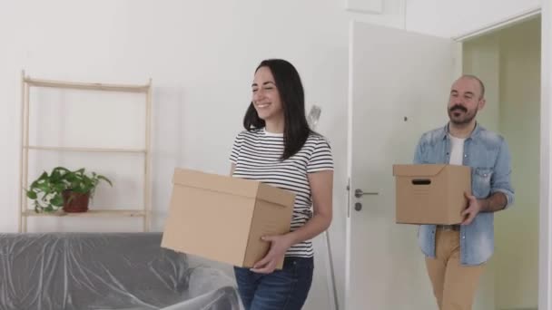 Feliz joven pareja casada mudándose en un nuevo hogar - Concepto de reubicación — Vídeos de Stock