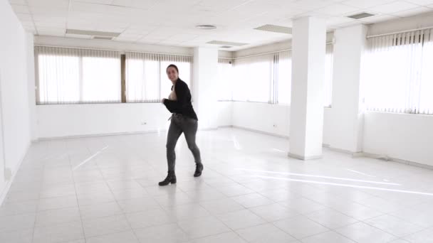 Alegre jovem agente imobiliário de aluguel dançando em um novo escritório vazio — Vídeo de Stock