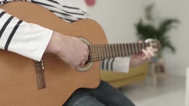 Närbild ung man händer spela gitarr samtidigt koppla av hemma — Stockvideo