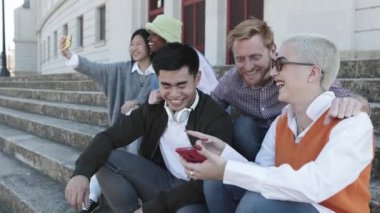 Gençler dışarıda akıllı cep telefonu kullanırken eğleniyorlar.