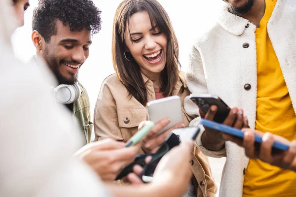 Молода група людей сміється за допомогою мобільного телефону на відкритому повітрі — стокове фото