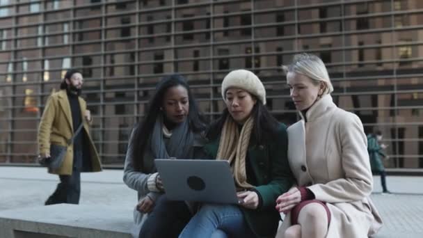 Tres mujeres de negocios jóvenes multirraciales que trabajan juntas en el ordenador portátil al aire libre — Vídeos de Stock