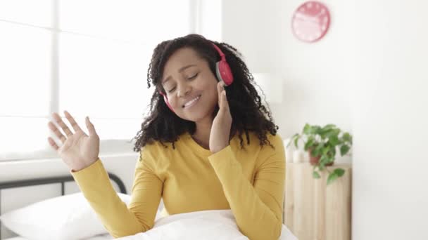Glädjande ung afrikansk amerikansk kvinna dansar medan du lyssnar på musik på sovrummet — Stockvideo