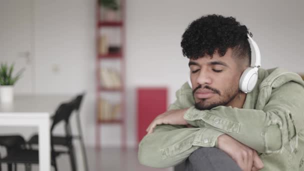Latino jongeman met gesloten ogen ontspannen thuis luisteren naar muziek — Stockvideo