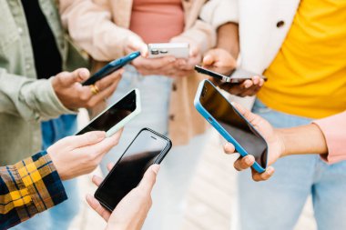 Dışarıda cep telefonu tutan çok ırklı bir grup genç öğrenci.