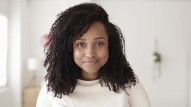 Evinden kameraya gülümseyen neşeli Brezilyalı genç kadın.