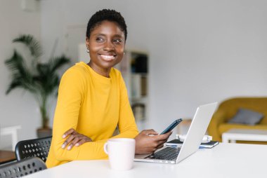 Cep telefonu kullanan ve işten izin alırken rahatlayan gülümseyen kadın.