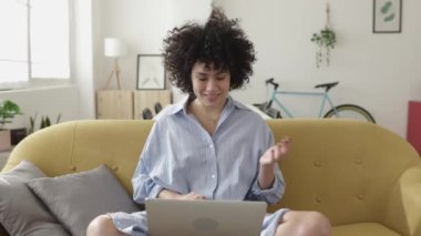 Genç yetişkin bir kadın evdeki dizüstü bilgisayarında bir video görüşmesi yapıyor.