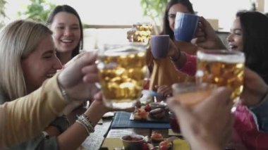 Gülümseyen çok ırklı bir grup genç birlikte kahvaltı ediyor ve gülüyor.