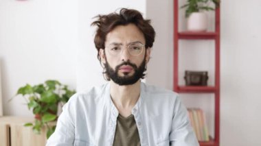 Hippi genç yetişkin bir adam kameraya video aracılığıyla bakıyor ve dinliyor.